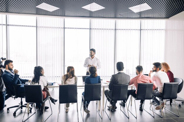 Photo row of unrecognizable business people sit in conference hall at business event.