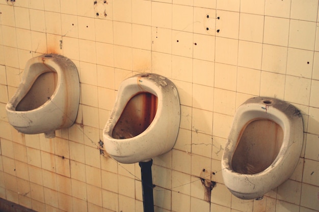 Photo row of urinals at abandoned public restroom