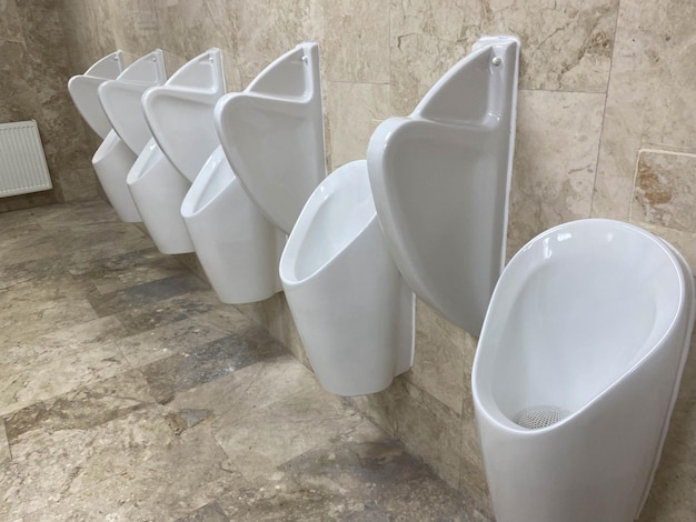 A Row Of Urinals In Tiled Wall In A Public Restroom