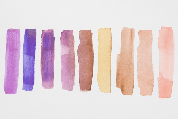 Photo row of violet and brown paints on white paper