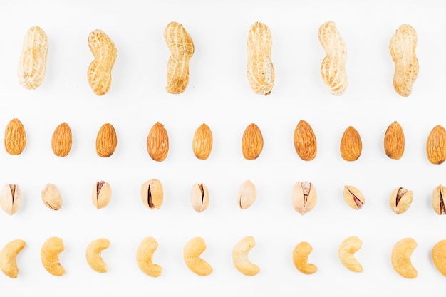 Row of walnuts; peanuts; almonds; pistachios and cashew nuts on white background