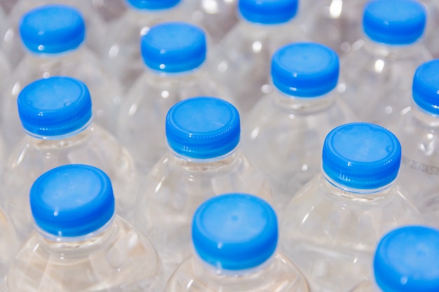 Foto fila di bottiglie d'acqua. bottiglie con tappi blu per acqua potabile