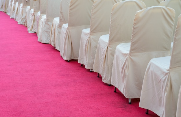 Photo row of white fabric chairs on red carpet