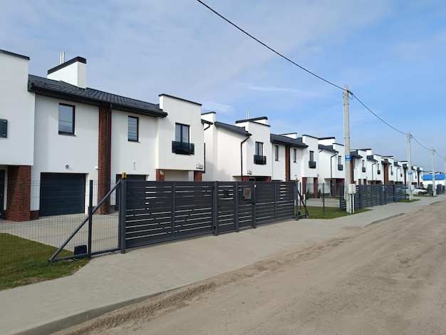 A row of white houses with a fenced in front of them.