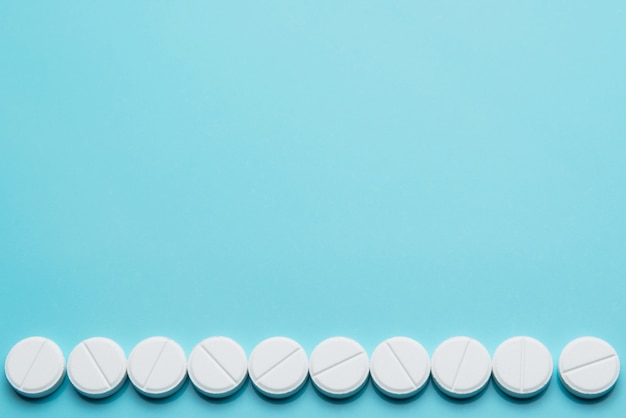 A row of white pills on a blue background.