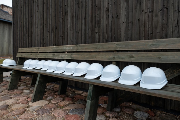 Photo row of white safety helmets lined up on a wooden bench against a dark timber background