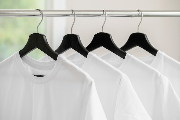 Row of white t-shirts on hangers hanging on rack