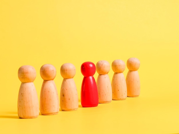 A row of wooden figures with a red color standing out from the rest