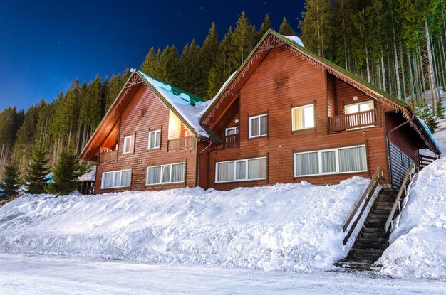 暗い空と夜の冬の雪に覆われた通りの木造住宅の行