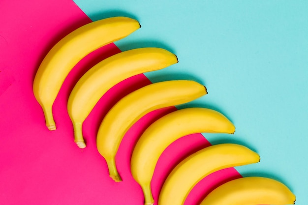 Row of yellow bananas on colorful background