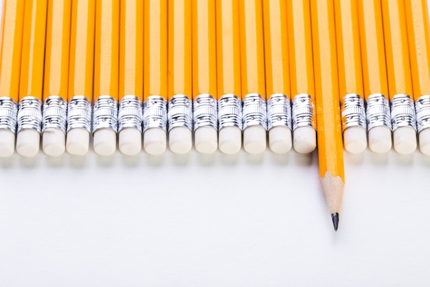 Row of yellow pencils with one sticiking out on white wall, Business and leadership concept