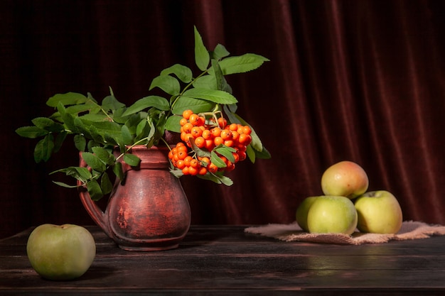 Rowan-tak met bessen en groene appels op donkere houten ondergrond en textiel met kopieerruimte