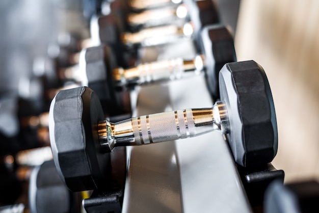 Rows of black metal dumbbells in the gym 