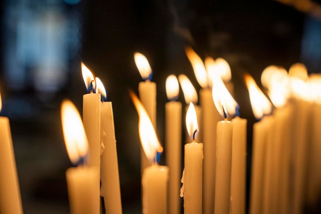 Rows of burning candles flame in the dark at church for worship