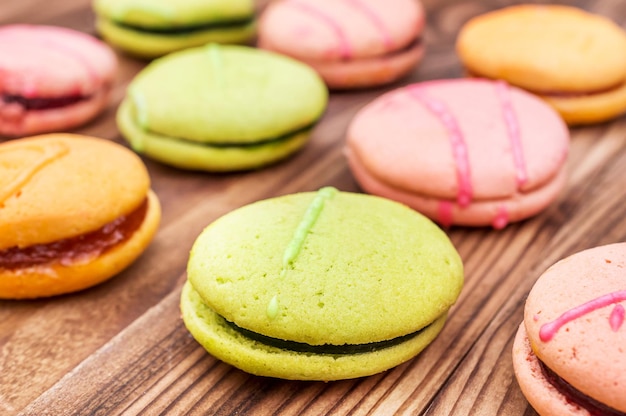 Photo rows of colorful macaroons on wooden background