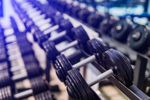 Rows of dumbbells on racks in the sport club Weight Training Equipment Image of iron dumbbells Closeup