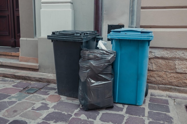 Foto file di bidoni della spazzatura di diversi colori in un vicolo del centro della città vicino a un bar o a un ristorante della città