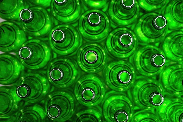 Rows of green glass bottles on the conveyor close-up. Industrial brewery