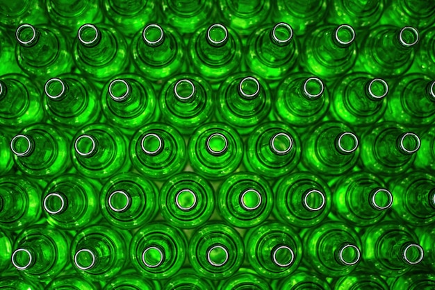 Photo rows of green glass bottles on the conveyor close-up. industrial brewery