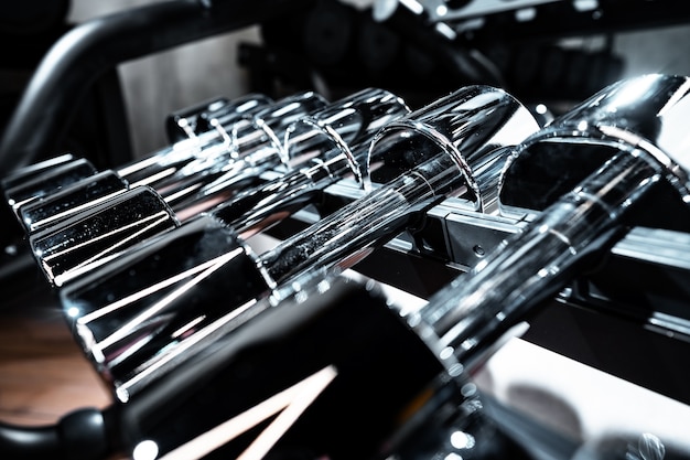 Rows of metal dumbbells on rack for bodybuilding in gym