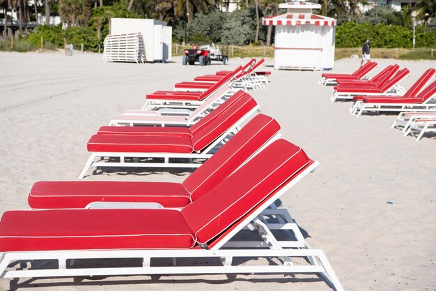 Rows of red sunchairs chaise lounges beach furniture on sand in summer