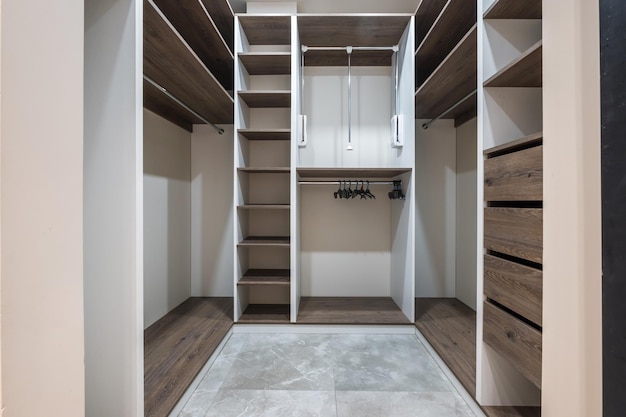 Rows of shelves and clothes hangers in the wardrobe empty big wardrobe room in modern apartment or hotel