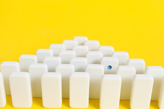 Rows white domino chips with one eye catching concept is\
individual and not like everyone else