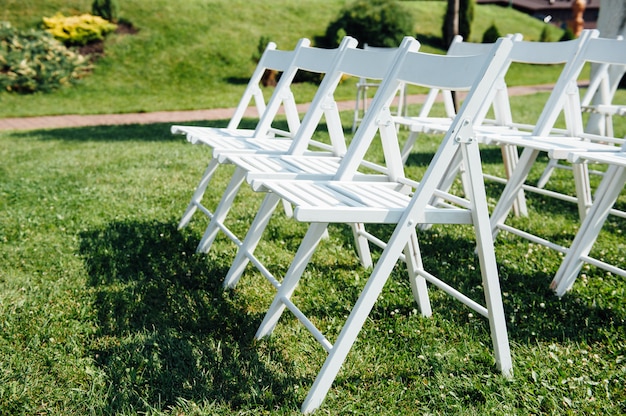 Rows of white folding chairs on lawn