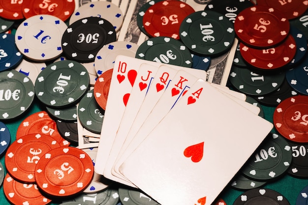 Royal flush in poker on the background of game chips and money dollars