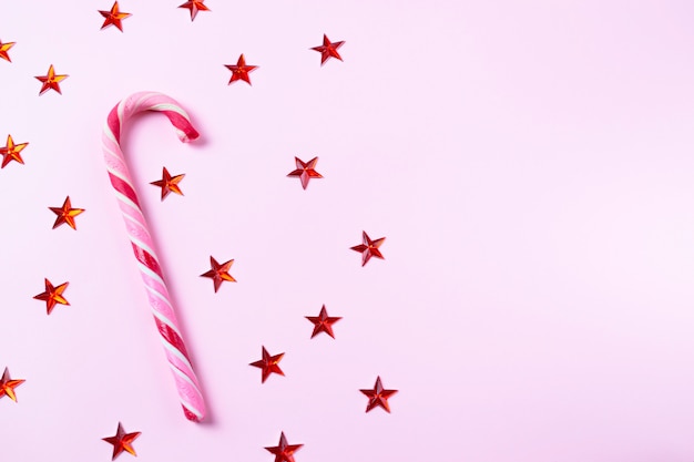 Roze achtergrond met riet van het Kerstmissuikergoed en glanzende sterren met exemplaarruimte