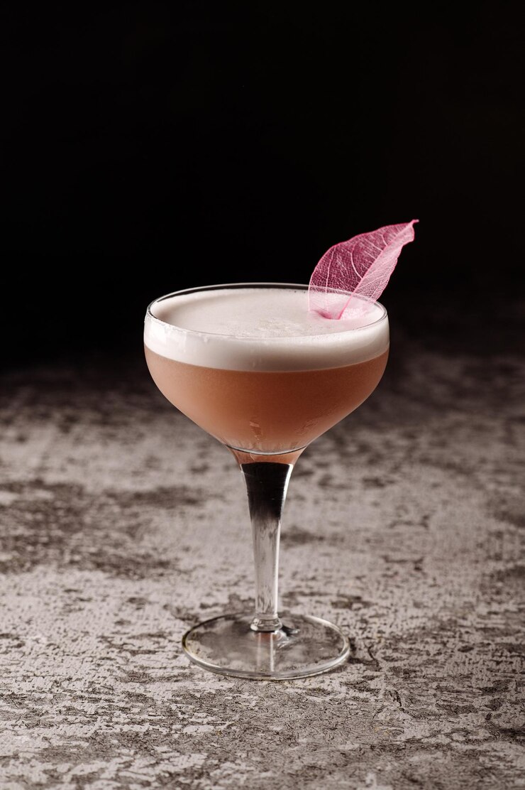 Roze alcoholische cocktail in hoog glas op zwarte achtergrond
