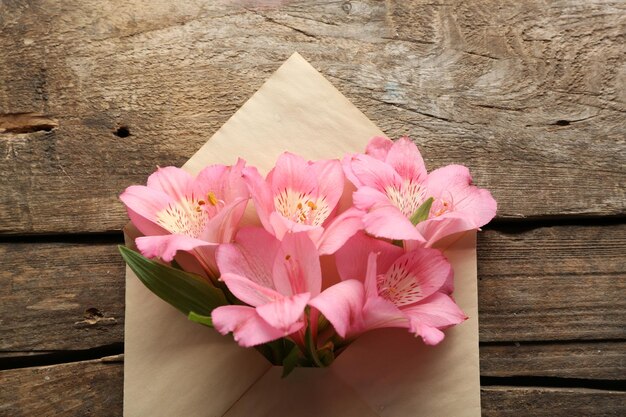 Roze alstroemeria in envelop op houten achtergrond