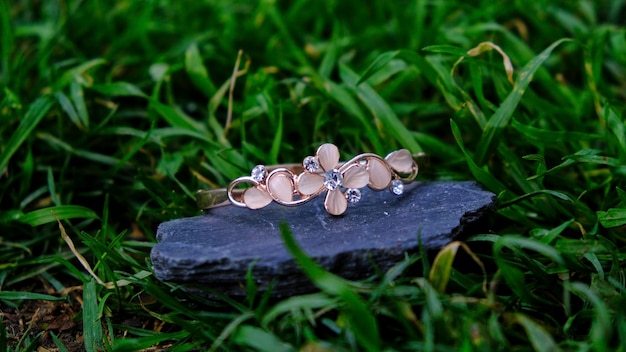 Roze armband met bloemen op een achtergrond van leisteen en gras