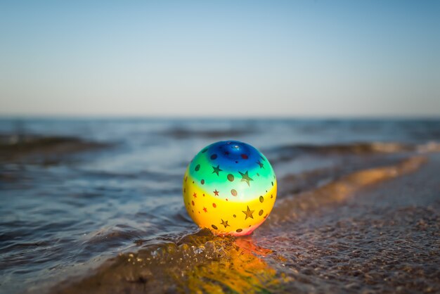 Foto roze bal op een zandstrand op een zonnige warme zomerdag door de golven van de zee