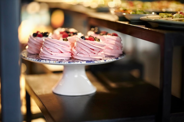 Roze bessen meringue met verse bessen op een witte standaard. Banketbakkerij.