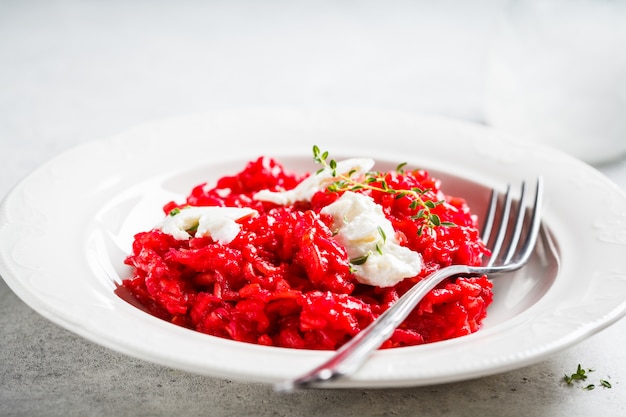 Roze bietenrisotto met feta-kaas in witte plaat.