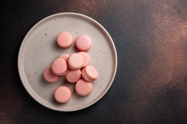 Roze bitterkoekjes op een bord op een donkere tafel