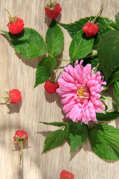 Foto roze bloem en rode framboos op licht hout