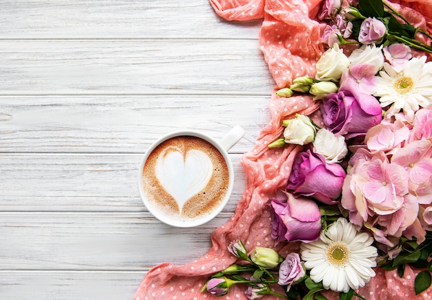 Roze bloemen en kopje koffie op een witte houten achtergrond