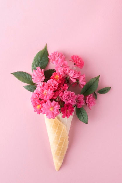 Roze bloemen in een wafelkegel op een roze achtergrond minimalistisch ontwerpidee