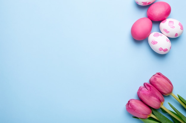 Roze bloementulpen en paaseieren op een blauwe oppervlakte