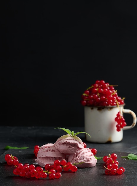 Roze bolletjes ijslolly's met rode aalbessen op een zwarte tafel IJs