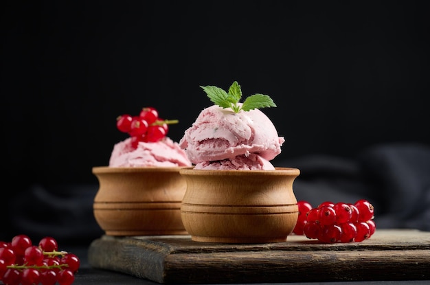 Roze bolletjes ijslolly's met rode aalbessen op een zwarte tafel IJs