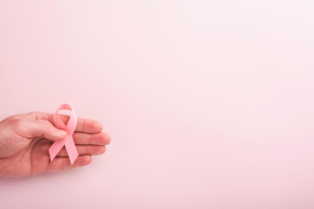 Roze borstkanker bewustzijn lint handen met roze lint op achtergronden borstkanker bewustzijn en oktober roze dag wereld kanker dag bovenaanzicht Mock up