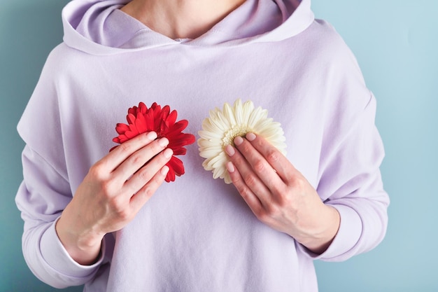 Roze borstkanker bewustzijn lint vrouwelijke handen met rode en witte gerbera op blauwe achtergronden Borstkanker bewustzijn en oktober roze dag wereld kanker dag bovenaanzicht Mock up