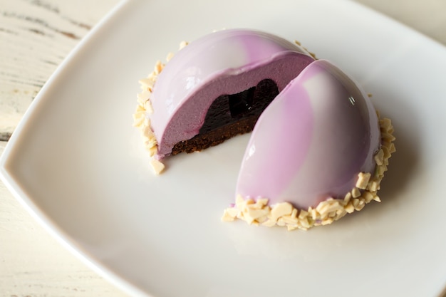 Roze cake met glazuur. Dessert met donkere vulling. Bosbessengelei en mousse. Snack op verjaardagsfeestje.