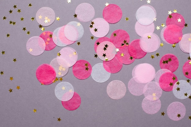 Roze confetti met gouden sterren op grijs met copyspace