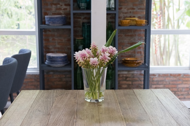 Roze de tulpenbloem van Siam in vaas op houten lijst dichtbij venster.