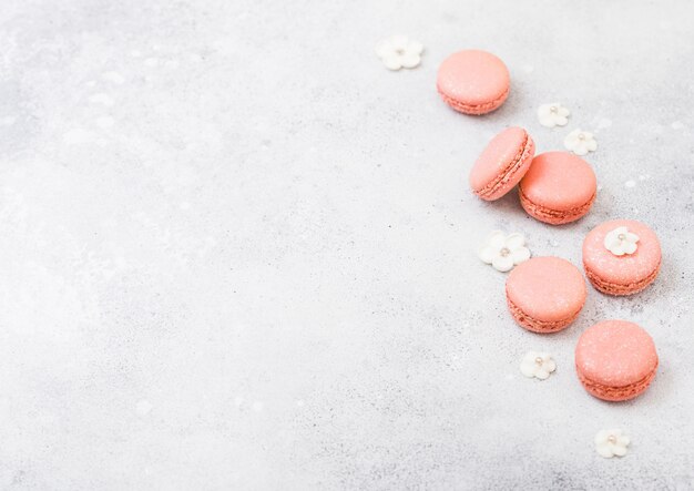 Roze dessert cake macaron of macaroon met witte zoete bloemen op stenen keuken.