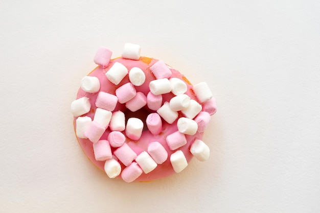 Roze donut met marshmallows op een witte achtergrond